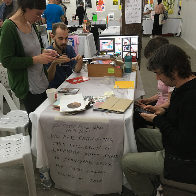 Photograph of people cataloguing works at the Frontyard table at Volume 2017 Book Fair